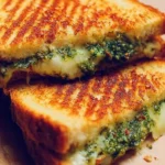 Mouthwatering pesto grilled cheese sandwich with melted cheese and fresh basil pesto