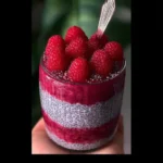Delicious raspberry chia pudding served in a glass with fresh berries on top.