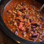 Delicious slow cooker chili served in a bowl, topped with cheese and cilantro.
